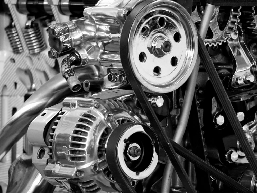 Detalhe do motor de carro com polias, correia e componentes metálicos da transmissão responsáveis pelo funcionamento das engrenagens automotivas.